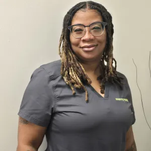 smiling woman with a grey merry maids uniform standing in front of a tan wall